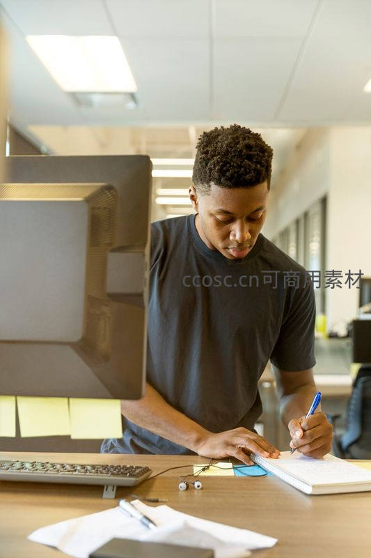 青年专注办公桌前记笔记