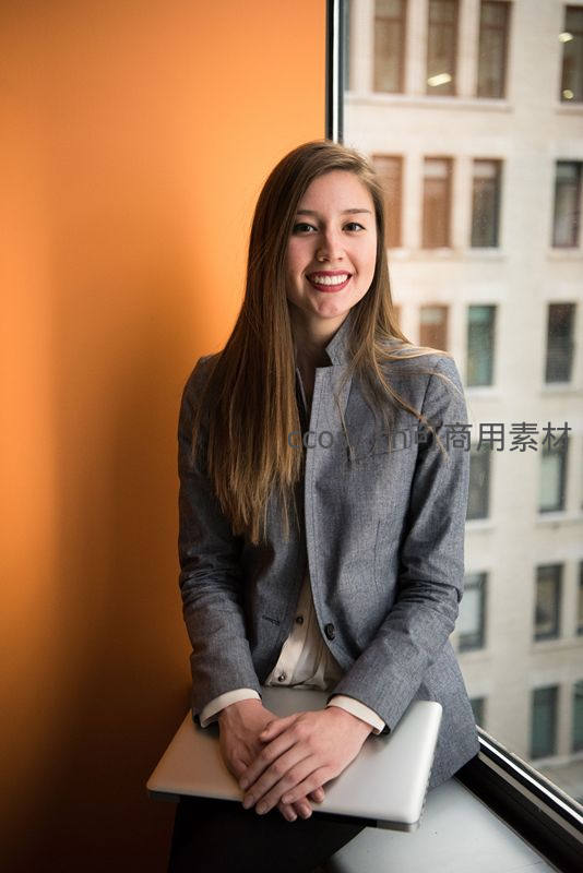 微笑女白领倚窗持电脑
