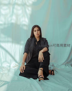 黑衣女子坐于浅蓝布景前凝视