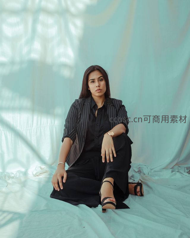 黑衣女子坐于浅蓝布景前凝视