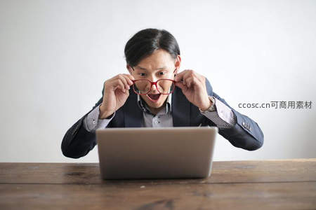 男子惊讶摘下眼镜紧盯笔记本电脑