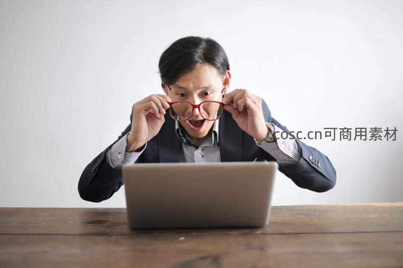 男子惊讶摘下眼镜紧盯笔记本电脑