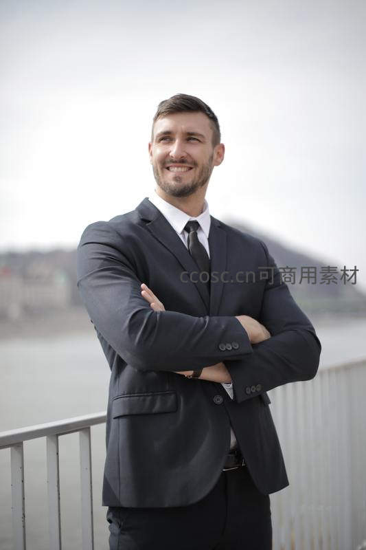 西装革履男士自信微笑双臂交叉
