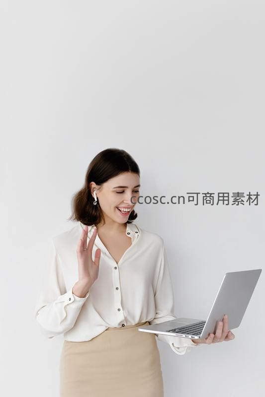 微笑女子手持电脑挥手致意