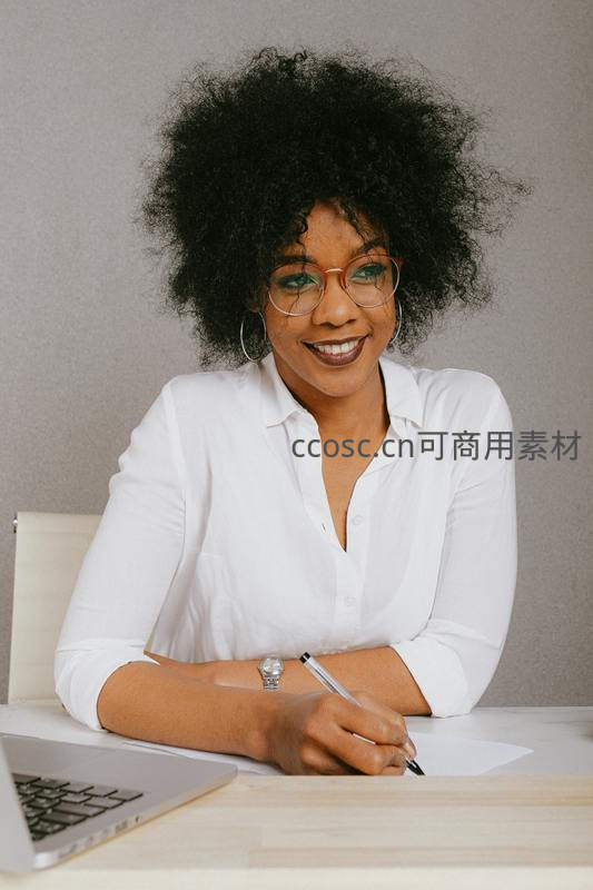 微笑女性在办公桌前书写文件