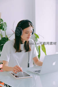 年轻女性戴耳机专注数字绘图