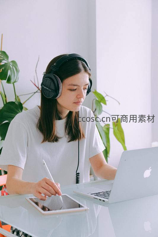 年轻女性戴耳机专注数字绘图