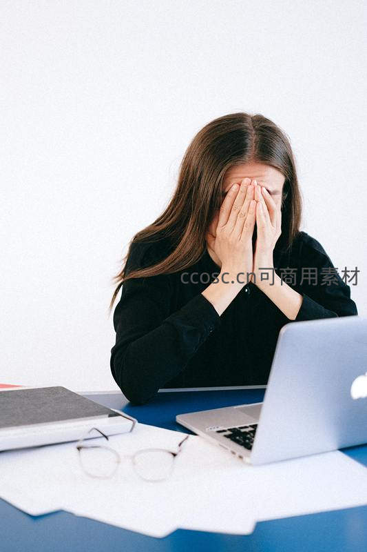 疲惫女性双手捂脸面对电脑