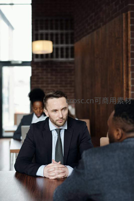 西装男士在咖啡馆内专注地与人对话