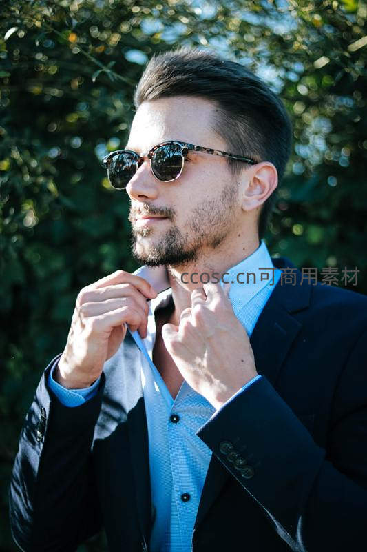 戴墨镜整理衣领的时尚男士
