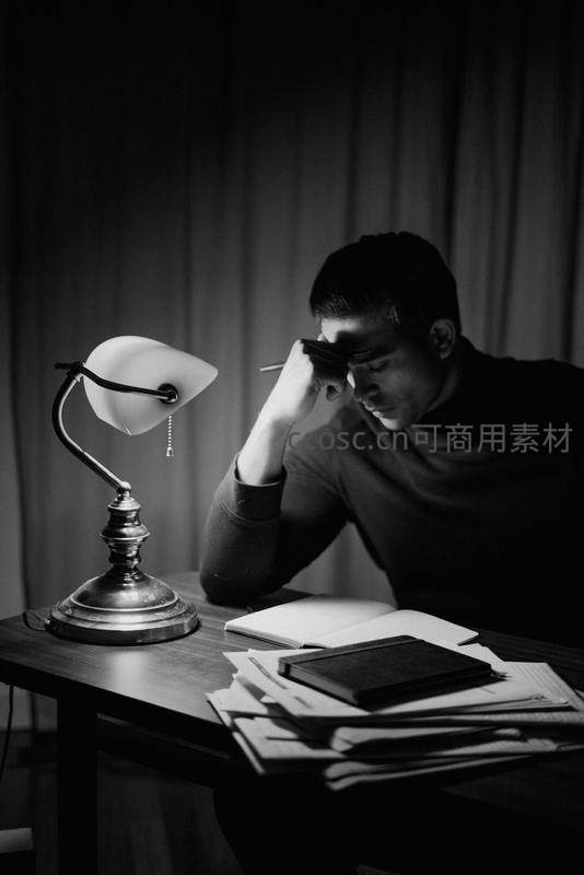 黑白照片中男子深夜伏案学习思考