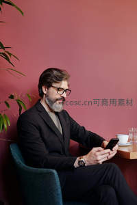 戴眼镜的绅士在咖啡馆使用手机
