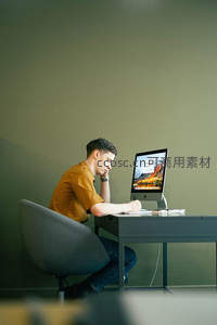 男子在简约办公室专注使用台式电脑