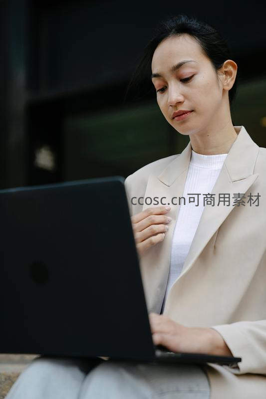 职场女性户外专注使用黑色笔记本电脑