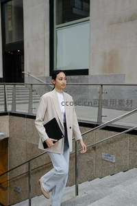 职业女性手拿文件夹走在现代办公楼台阶