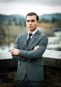 灰西装男士双臂交叉立桥头