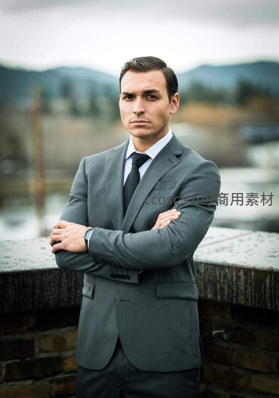 灰西装男士双臂交叉立桥头