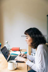 侧脸女性专注在木桌前敲打键盘