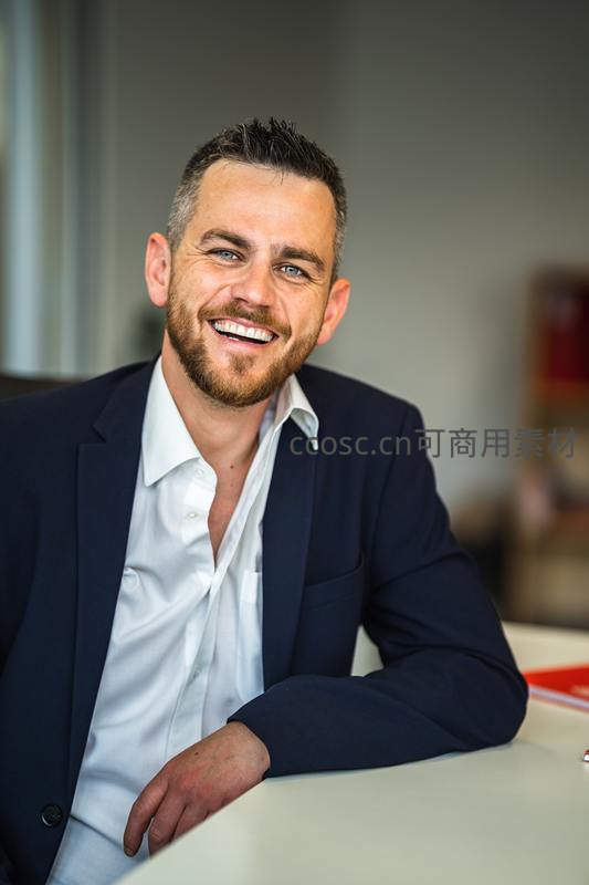 微笑的商务男士靠在办公桌前