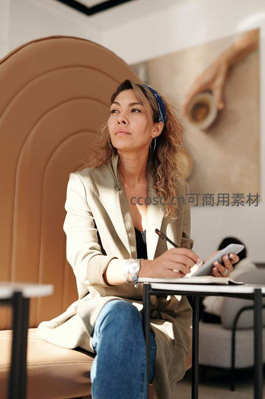 女性在咖啡馆中思考并记录灵感