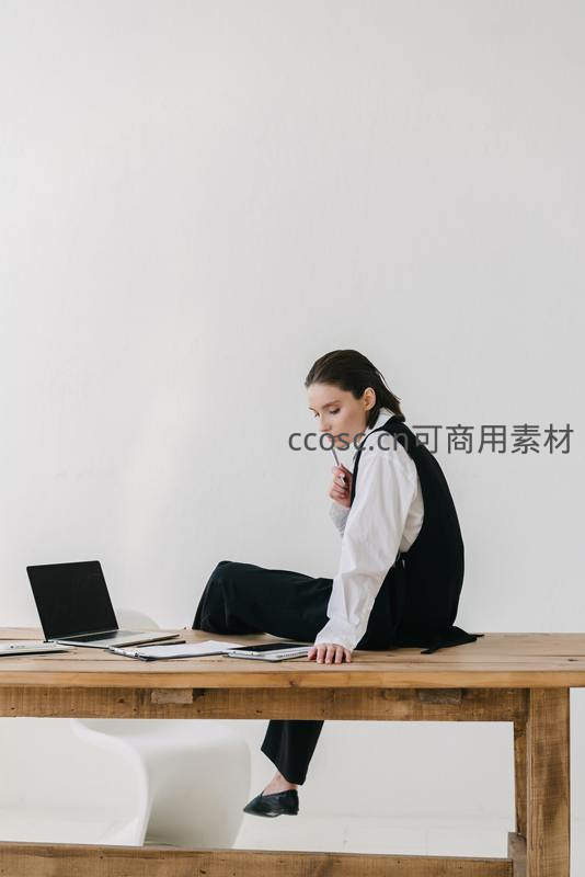 女子坐在长桌边低头沉思