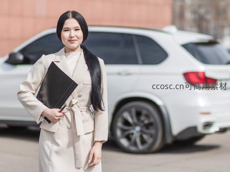 职业女性手持文件夹站在汽车旁