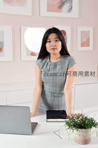 职场女性站立办公桌前凝视前方