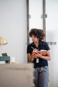卷发女性站立书写笔记专注工作