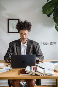 西装女性在书桌前使用笔记本电脑
