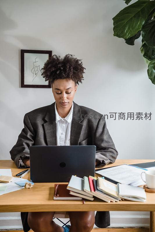 西装女性在书桌前使用笔记本电脑