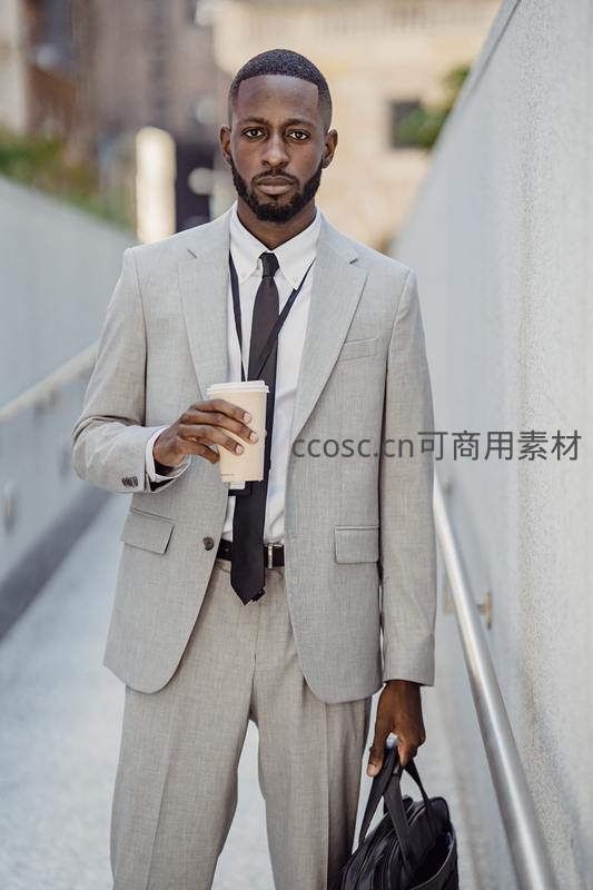 手提公文包的商务男士手持咖啡行走
