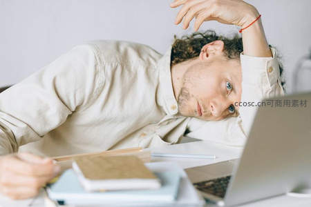 疲惫男子趴在桌上看着电脑