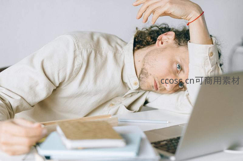 疲惫男子趴在桌上看着电脑