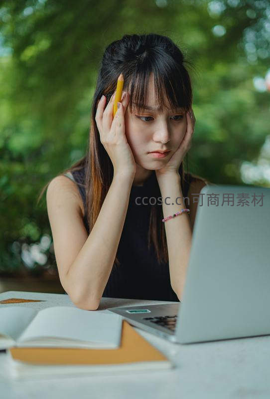 专注学习的年轻女性在户外书桌前