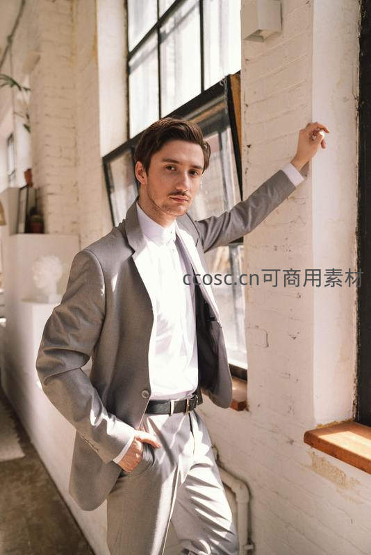 西装革履的男士靠墙凝视镜头