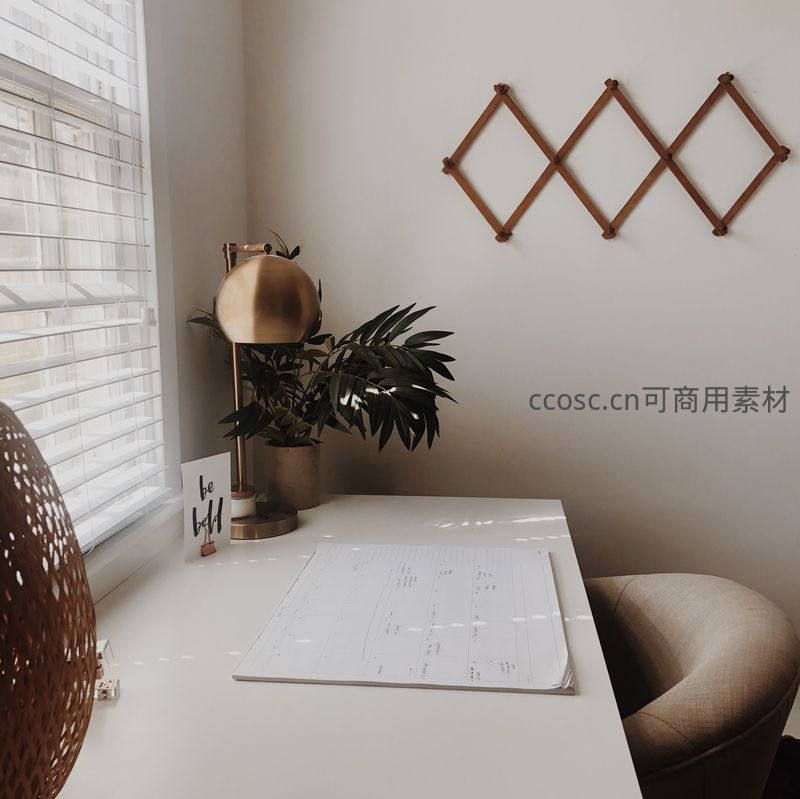 简约白色书桌角落，绿植与铜灯点缀