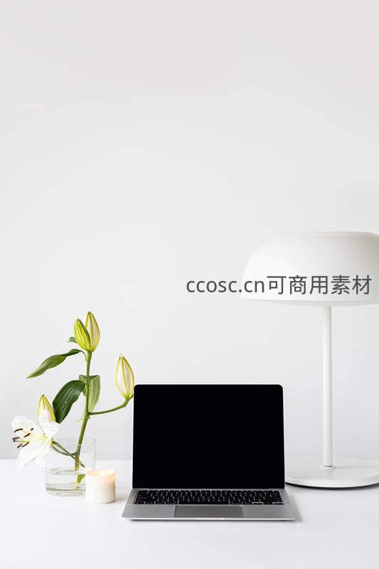 极简白色书桌上的笔记本电脑与百合花