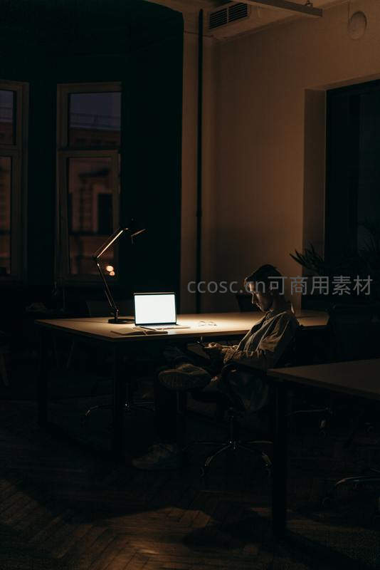 深夜办公室里台灯下的专注工作者