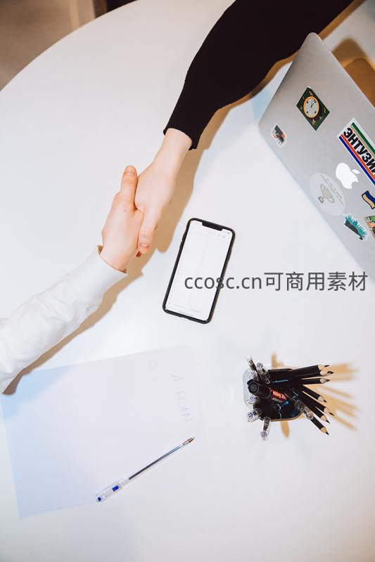 两人在办公桌前握手庆祝成功