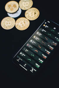 黑色背景下手机与实体比特币金币特写