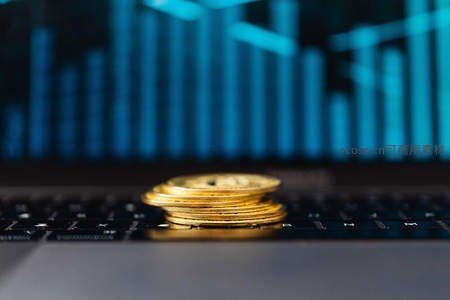 金色硬币叠放于显示数据图表的键盘上