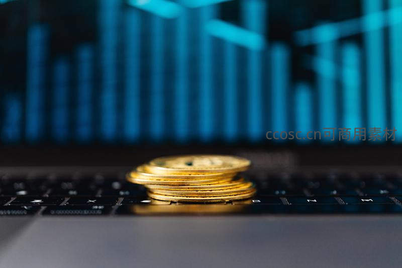 金色硬币叠放于显示数据图表的键盘上