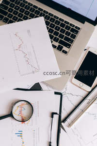 桌面散落财报文件与放大镜聚焦曲线图
