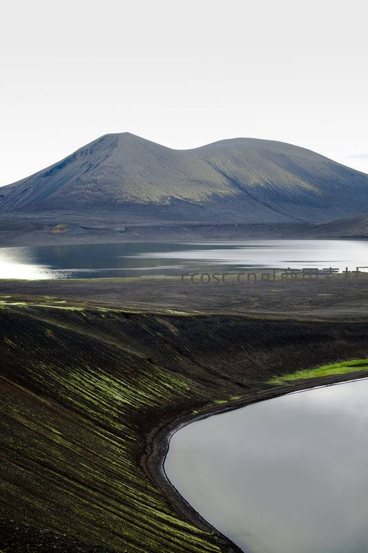 火山湖畔苔原绿，远山静默映水间