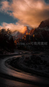 蜿蜒山路穿雪谷，夕照云霞染峰峦
