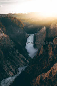 峡谷瀑布在夕阳下倾泻而下，水雾弥漫
