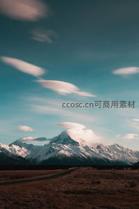 公路延伸向雪峰，帽状云朵舞天际