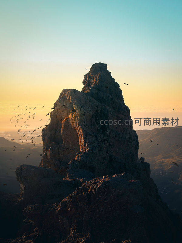 夕阳孤峰剪影，群鸟盘旋天际