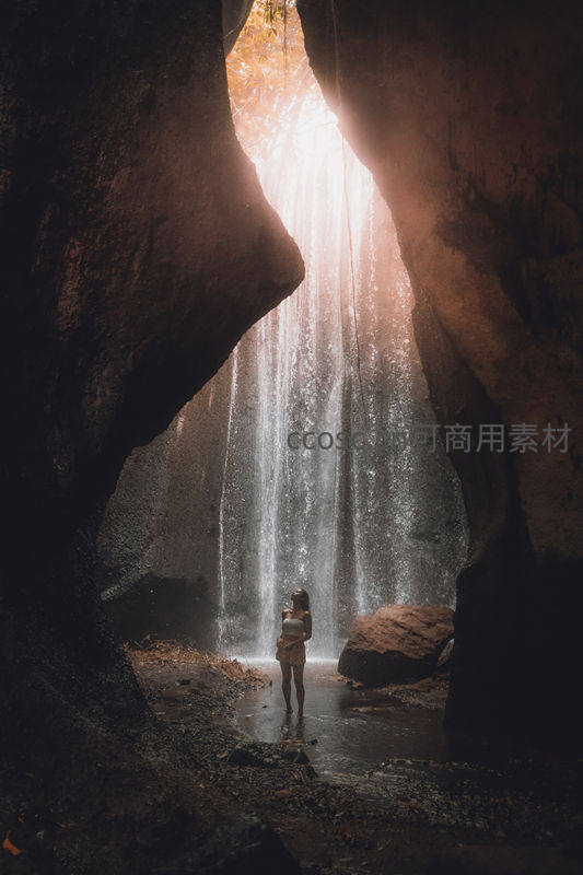洞穴瀑布倾泻而下，人影伫立显渺小