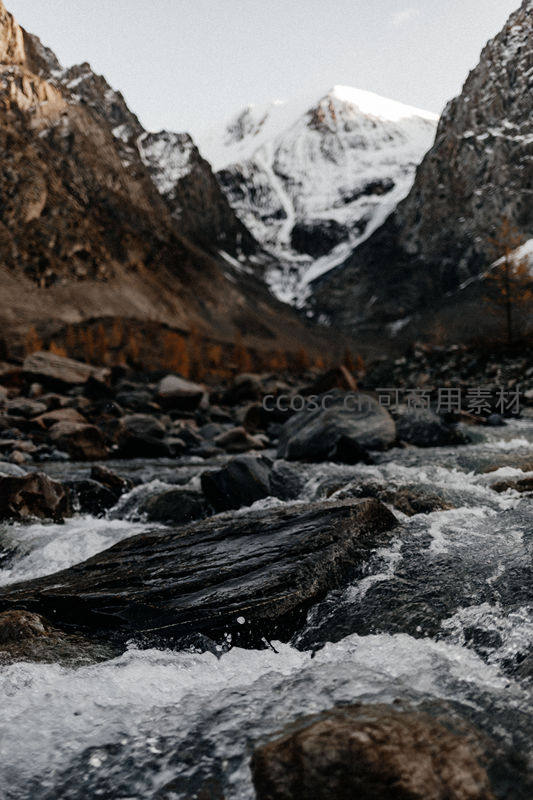 峡谷激流穿石而过，远山雪峰巍峨耸立